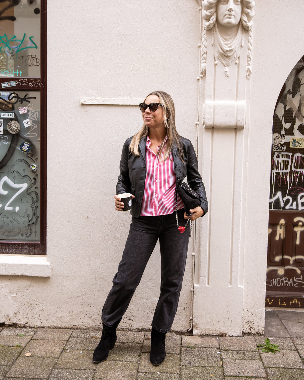 Bluse Blancah in Rot gestreift unter schwarzer Lederjacke Linneah, zur Jeans, Kaffee in der Hand