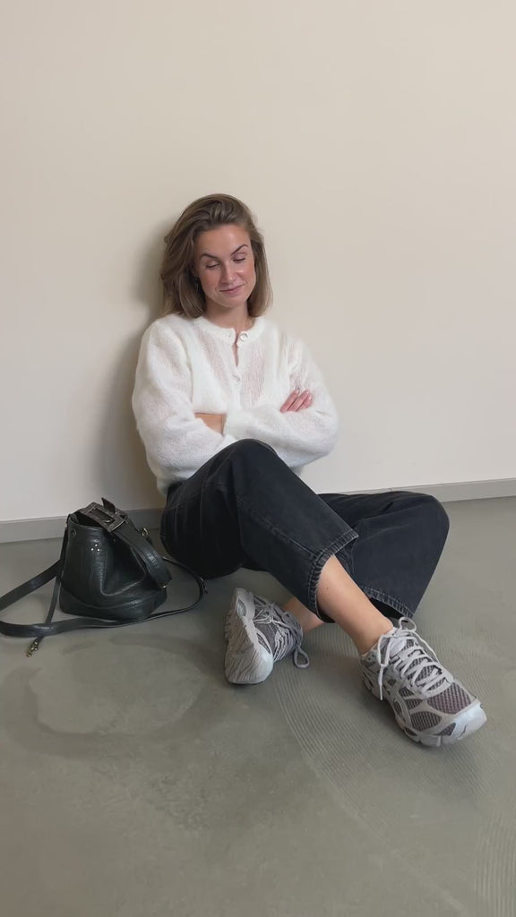 Strickjacke Charlotteh in Panna im Video: im Sitzen an der Wand, zur schwarzen Jeans